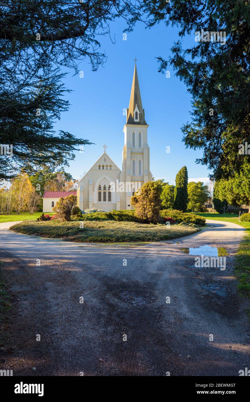 Blick auf die Evandale Kirche und ihren spektakulären Turm, eingerahmt von großen Bäumen in der kulturell bedeutenden Stadt Evandale in Tasmanien. Stockfoto