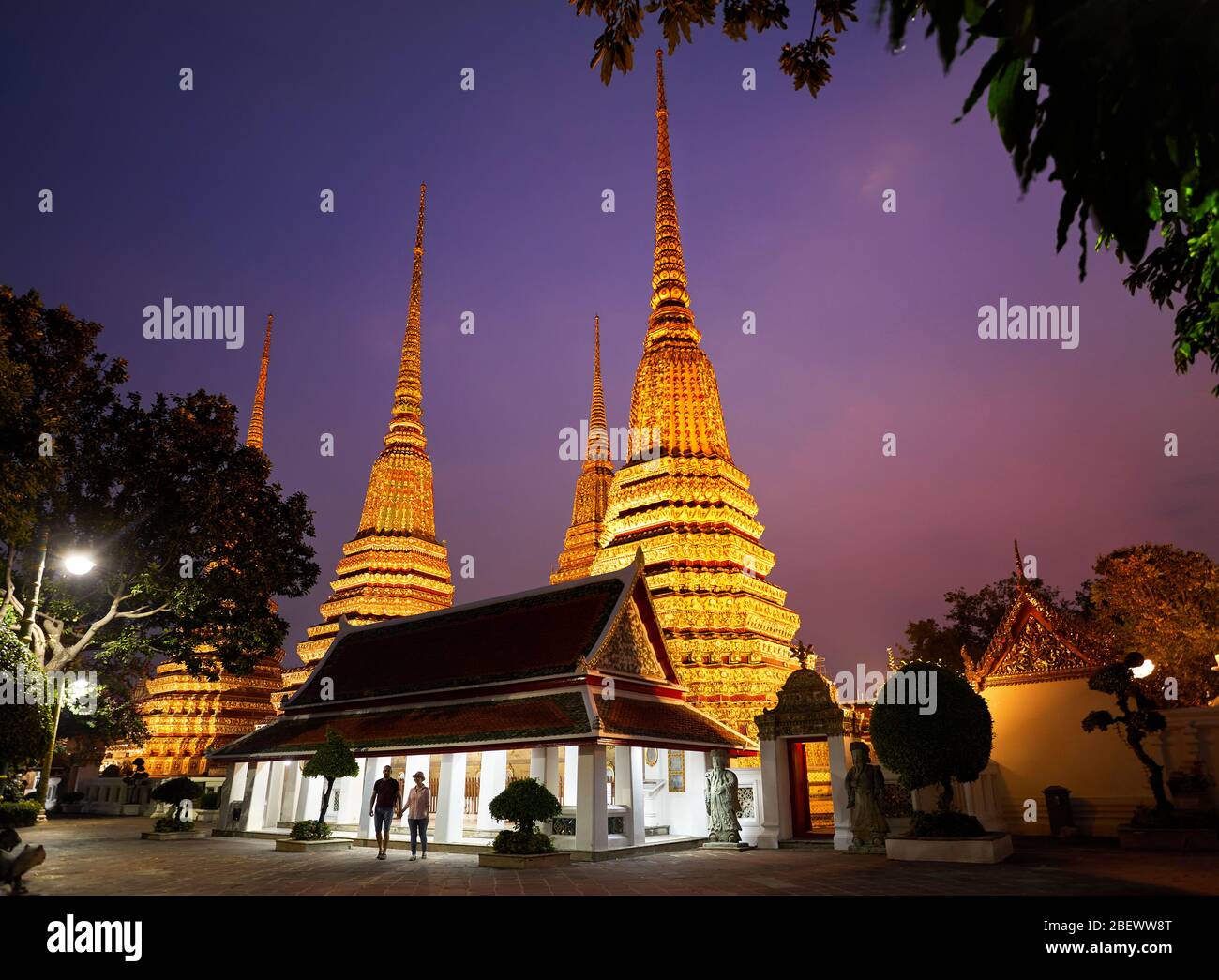 Junges Paar in Silhouette in der Buddhistischen Tempelanlage Wat Pho in Bangkok lila Nachthimmel in Thailand Stockfoto