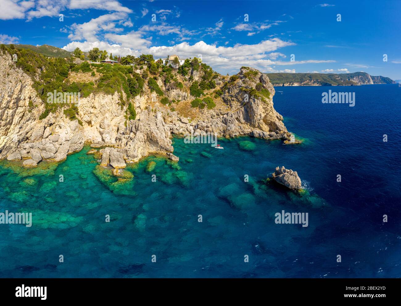 Luft mediterrane Landschaft mit türkisfarbenem Meer. Blick auf eine Insel Korfu in Griechenland. Paleokastritsa Kloster von einer Drohne. Boot mit Touristen auf einem Be Stockfoto