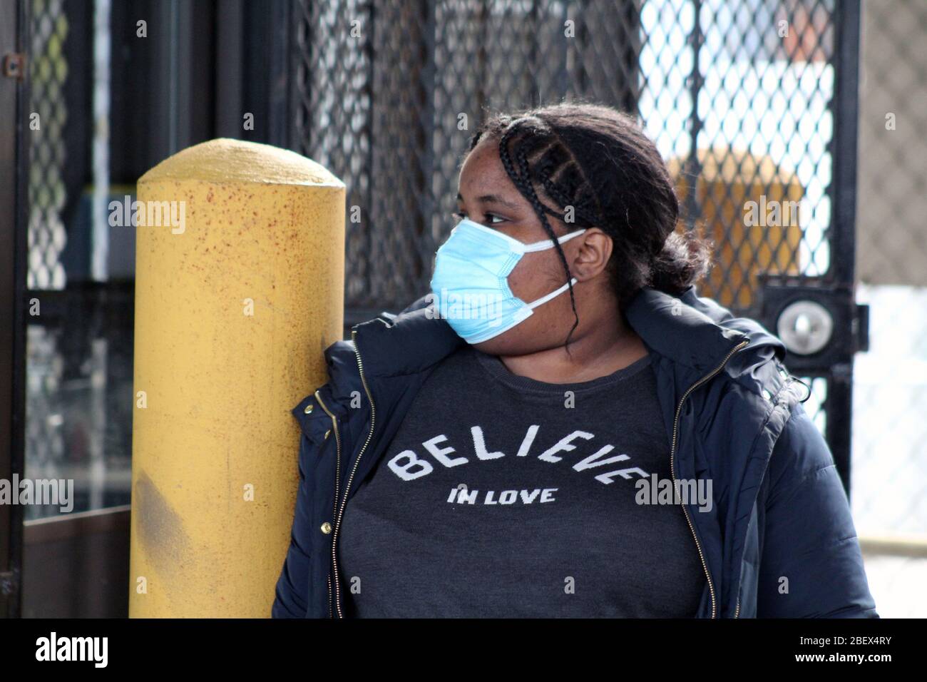 New York, New York, USA. April 2020. Diese Frau, mit einem Gesicht maskiert, nimmt ihr Auto auf einem Mietparkplatz in der Nähe der größten provisorischen Leichenkeller außerhalb des Bellevue Hospital in New York inmitten des Coronavirus Ausbruch geparkt. Auf ihrem blauen T-Shirt steht "Believe in love".Quelle: Marie Le BLE/ZUMA Wire/Alamy Live News Stockfoto