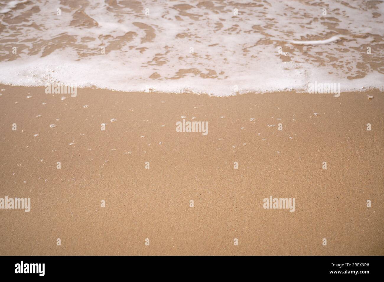 Ruhige Wellen, die an einem sonnigen Tag über einem Strand liegen Stockfoto