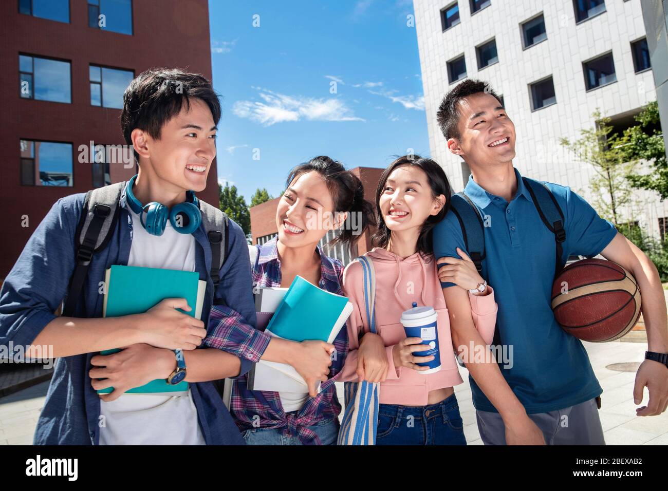 Vier Studenten auf dem Campus halten eng zusammen Stockfoto