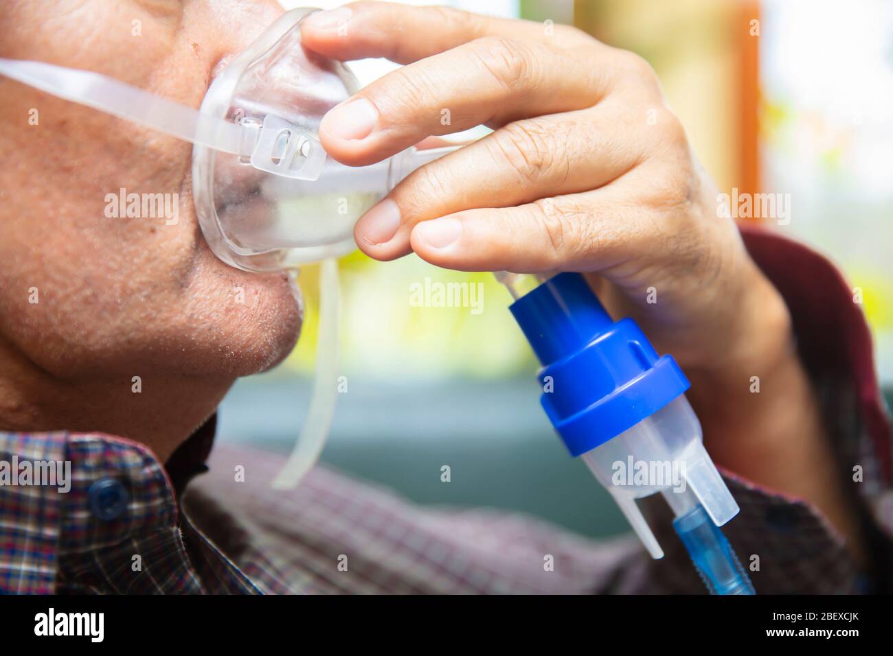Leitender Mann, der medizinische Geräte für die Inhalation mit Atemschutzmaske verwendet, Vernebler im Zimmer Stockfoto