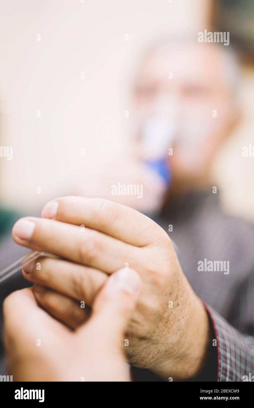 Leitender Mann, der medizinische Geräte für die Inhalation mit Atemschutzmaske verwendet, Vernebler im Zimmer Stockfoto