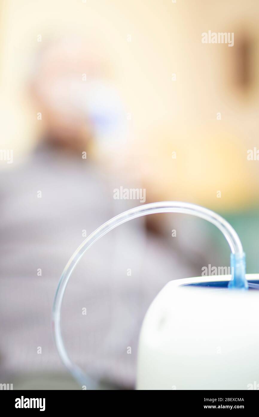 Leitender Mann, der medizinische Geräte für die Inhalation mit Atemschutzmaske verwendet, Vernebler im Zimmer Stockfoto