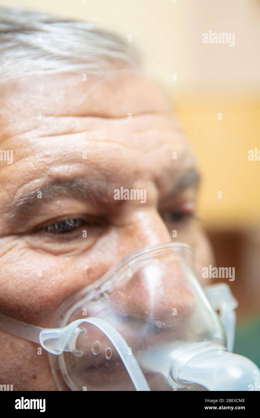 Leitender Mann, der medizinische Geräte für die Inhalation mit Atemschutzmaske verwendet, Vernebler im Zimmer Stockfoto