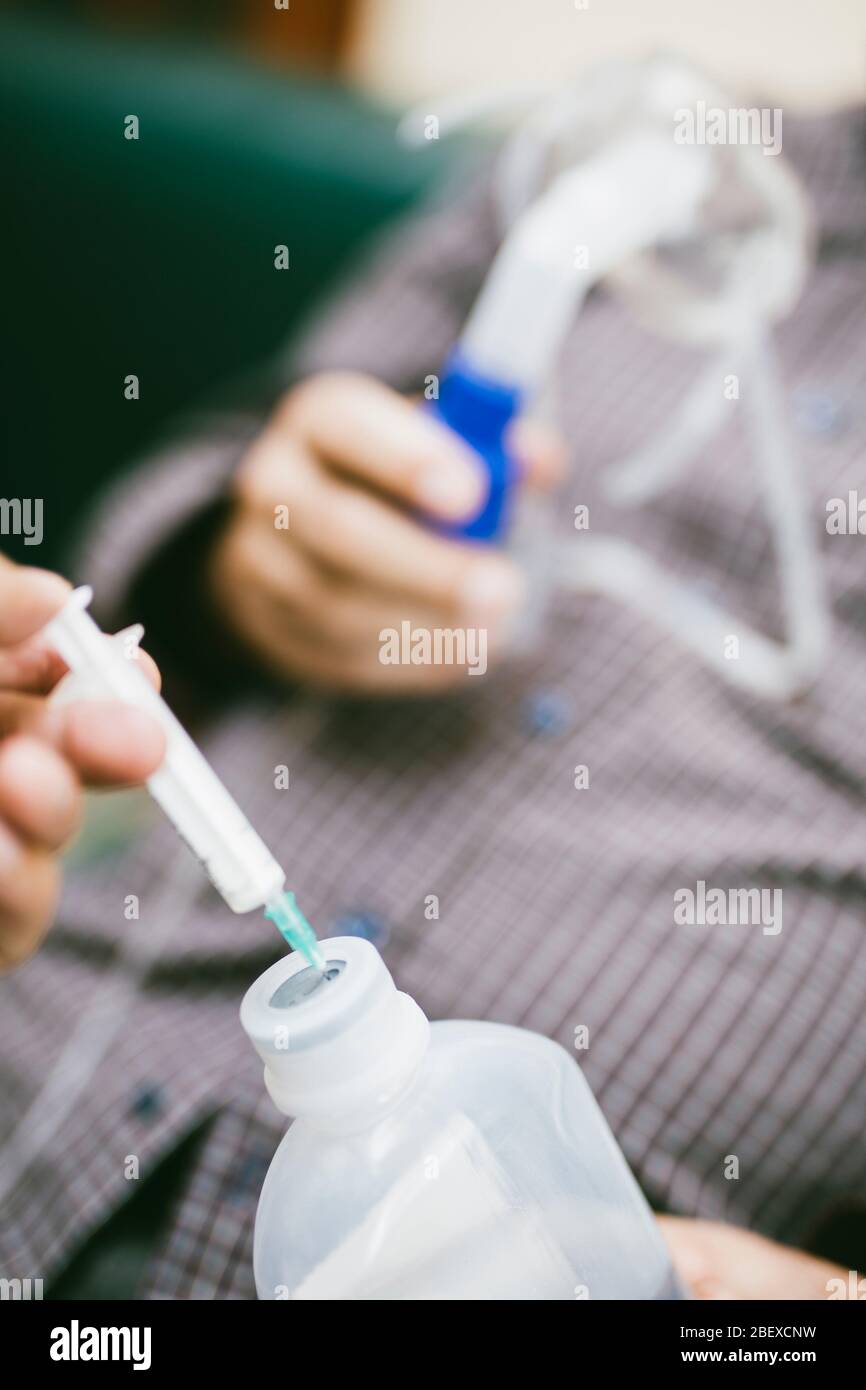 Vorbereitung des Kompressorverneblers für den Einsatz auf älteren Mann mit Atemschutzmaske, Vernebler im Raum Stockfoto