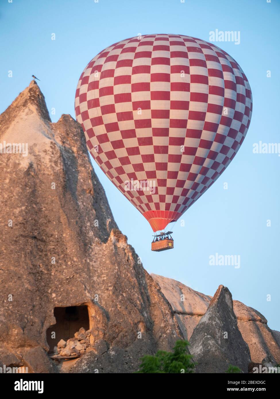 Rot-weißer Heißluftballon über Höhlenhaus in kappadokien Stockfoto