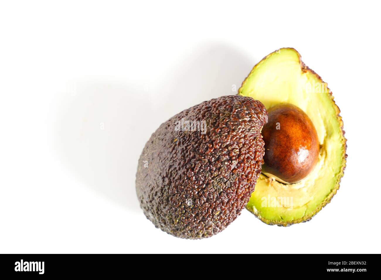 Ein Avocado, das in zwei Hälften geschnitten wurde, um den Kern vor einem weißen Hintergrund zu enthüllen Stockfoto