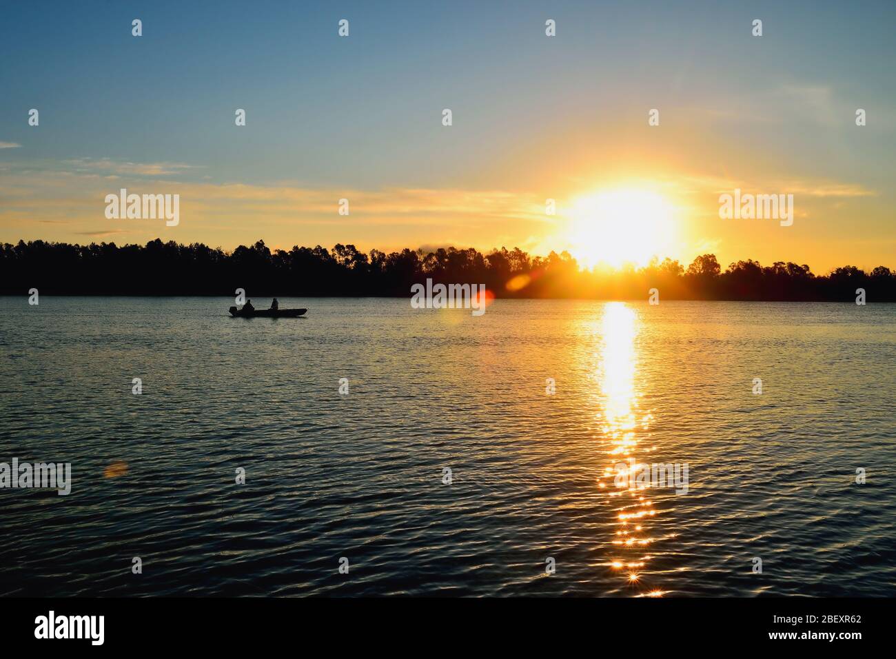 Sonnenaufgang auf dem Fluss. Ein Boot mit Anglern. Schöne Reflexe auf dem Wasser. Stockfoto