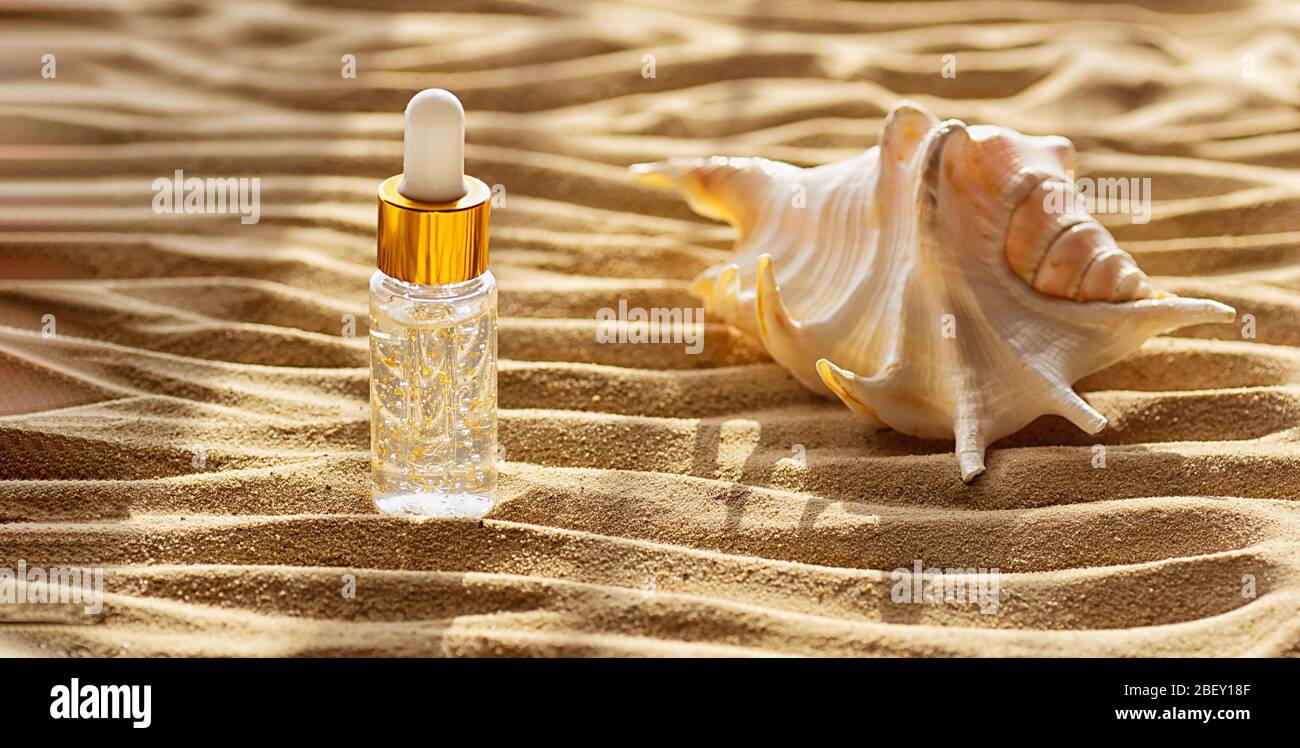 Feuchtigkeitsspendende Gesichtsserum in einer transparenten Flasche enthält Partikel von Gold. Beauty- und Wellness-Konzept. Stockfoto