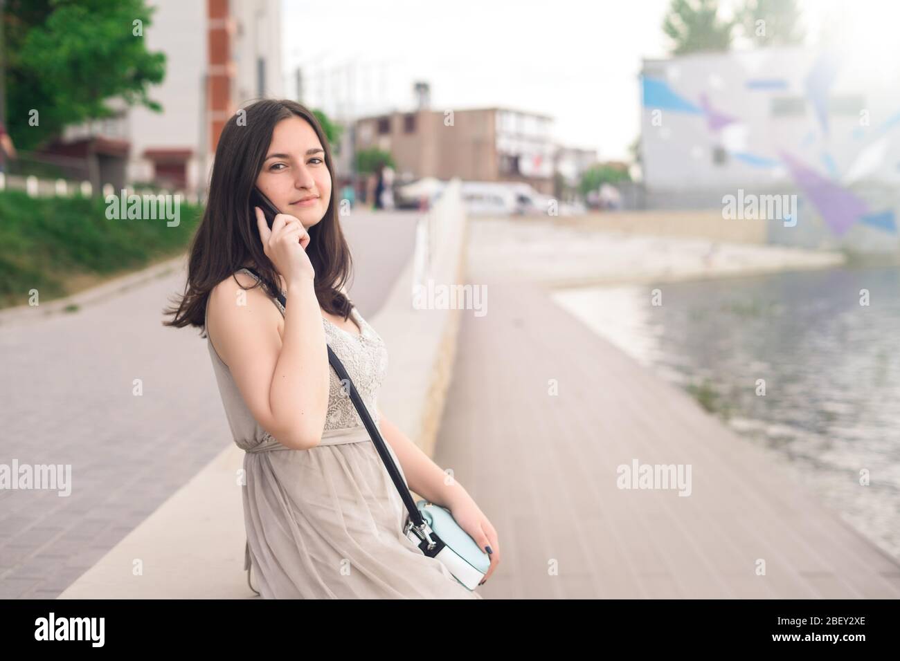 Mädchen sprechen am Wasser per Telefon. Mädchen in der Stadt an einem Sommertag Stockfoto