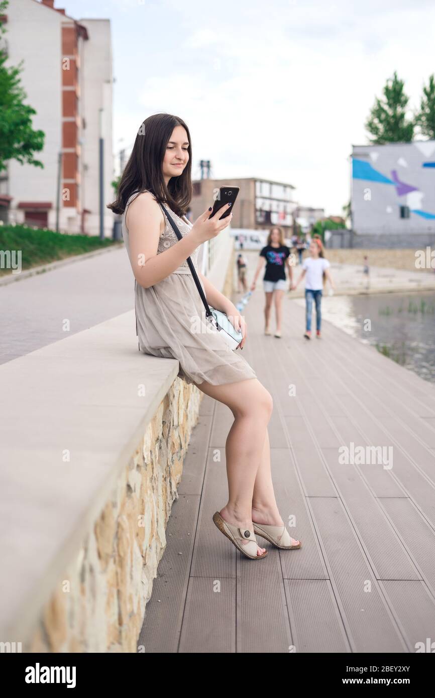 Mädchen mit Telefon am Pier. Hübsches Mädchen, das Selfies in der Stadt macht Stockfoto