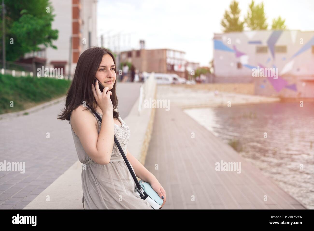 Mädchen sprechen am Wasser per Telefon. Mädchen in der Stadt an einem Sommertag Stockfoto