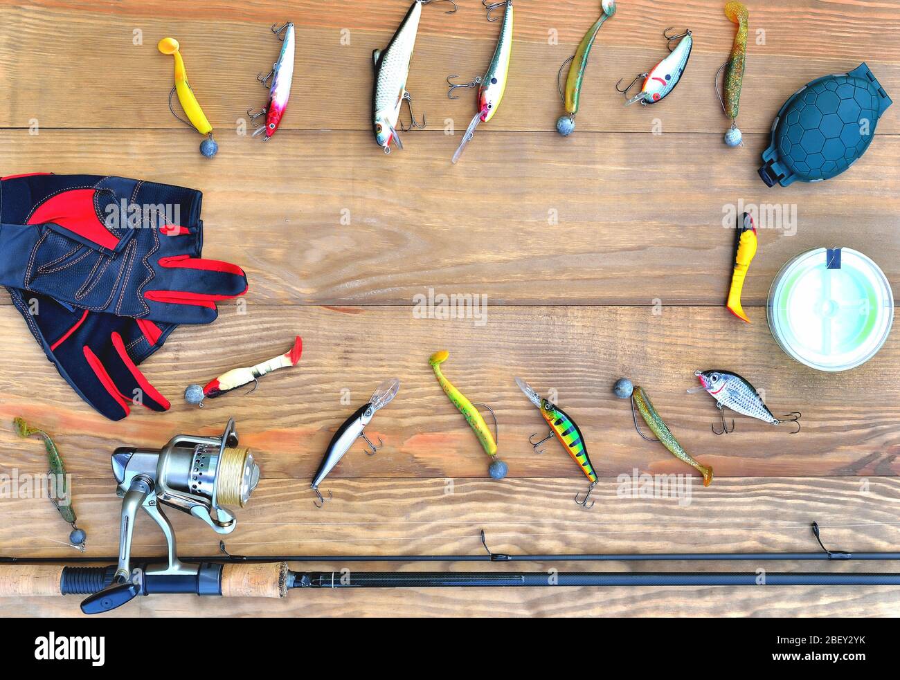 Angelzubehör Angelrute, Rolle mit Angelschnur, Silikon Köder und Köder, Spinnhandschuhe und Zubehör-Box auf Holzgrund, Nahaufnahme, Stockfoto