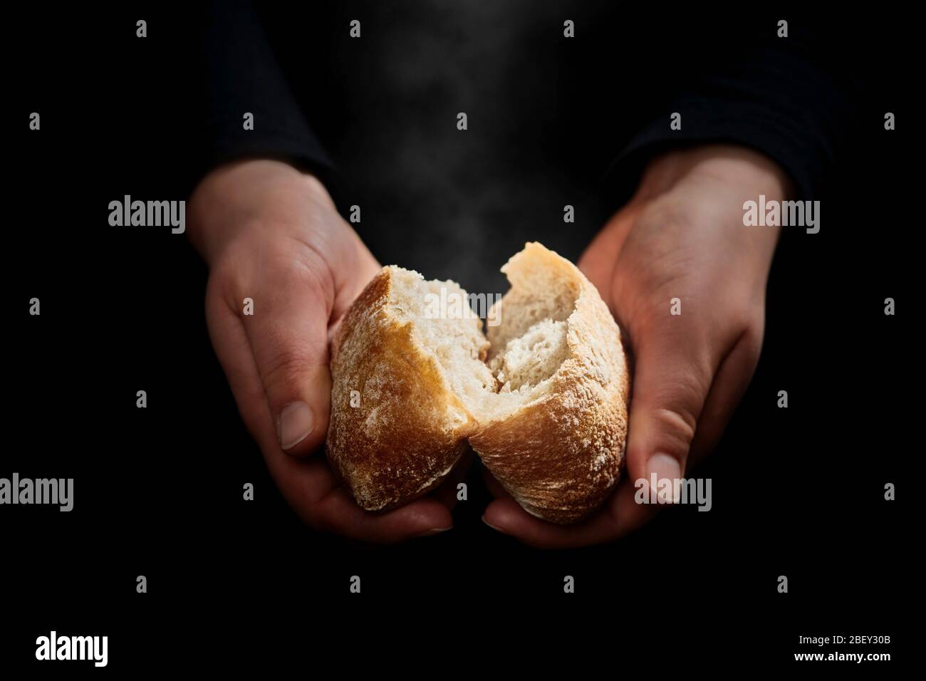 Hände brechen ein frisches, noch dampfendes Brötchen... Stockfoto