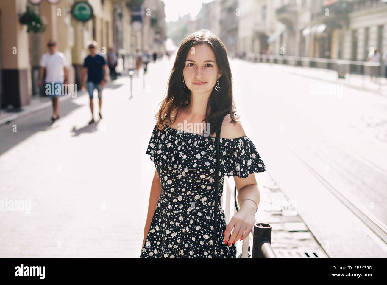 Wunderschöne lächelnde Frau, die auf einer überfüllten Straße in der Stadt läuft Stockfoto