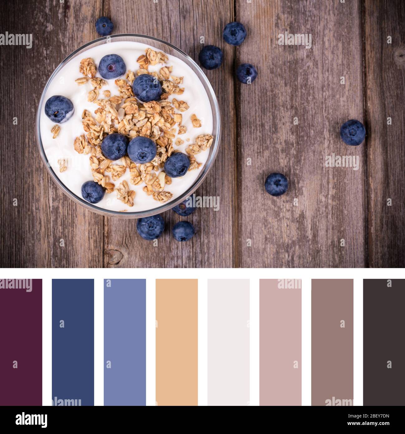 Joghurt mit Heidelbeeren und Müsli auf altem Holzhintergrund. In einer Farbpalette mit kostenlosen Farbfeldern. Stockfoto