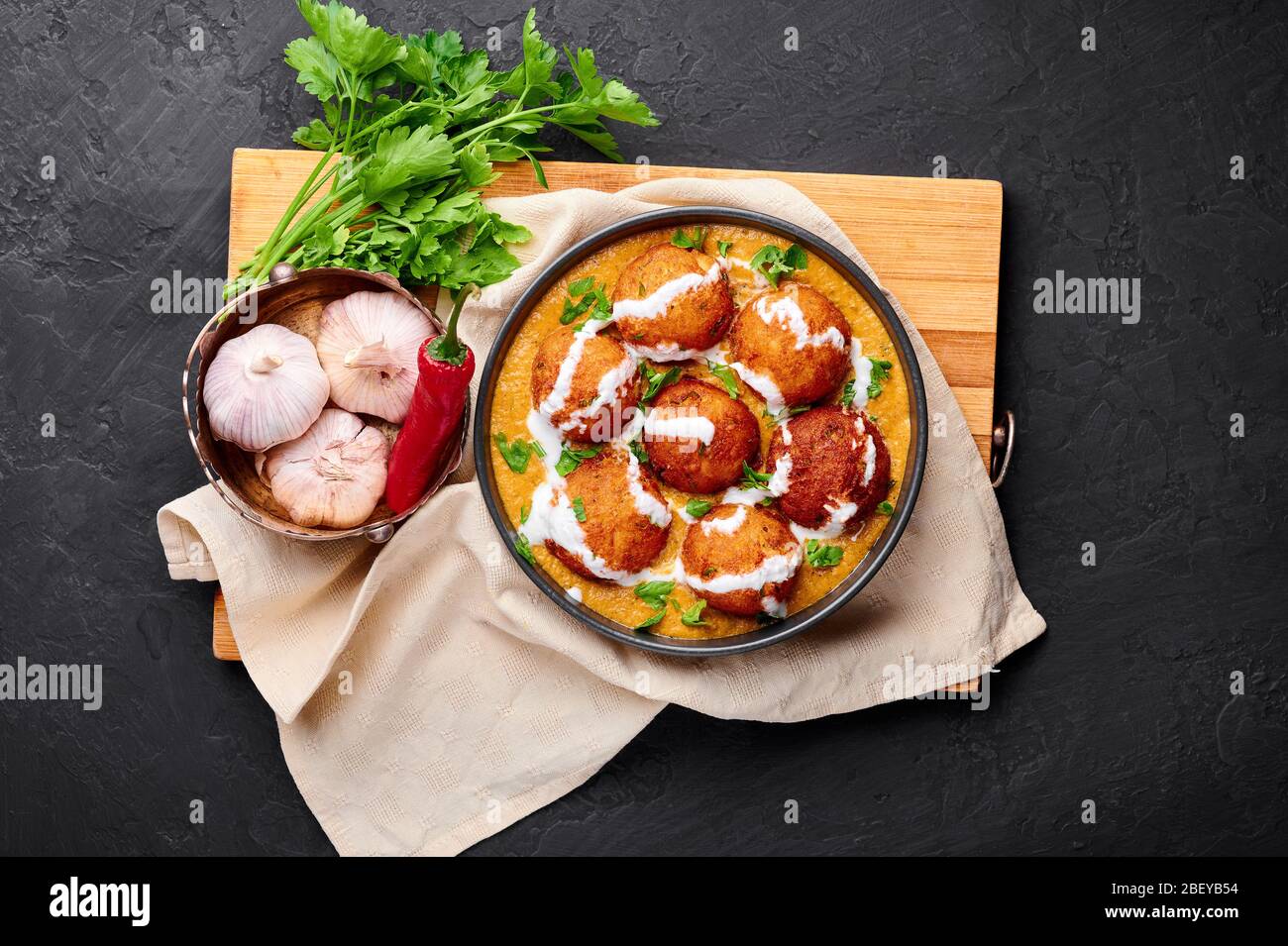 Malai Kofta Curry in schwarzer Schale auf dunklem Schiefergrund. Malai Kofta ist ein Gericht der indischen Küche mit Kartoffeln und Paneer Käse frittierten Bällchen in Zwiebel t Stockfoto