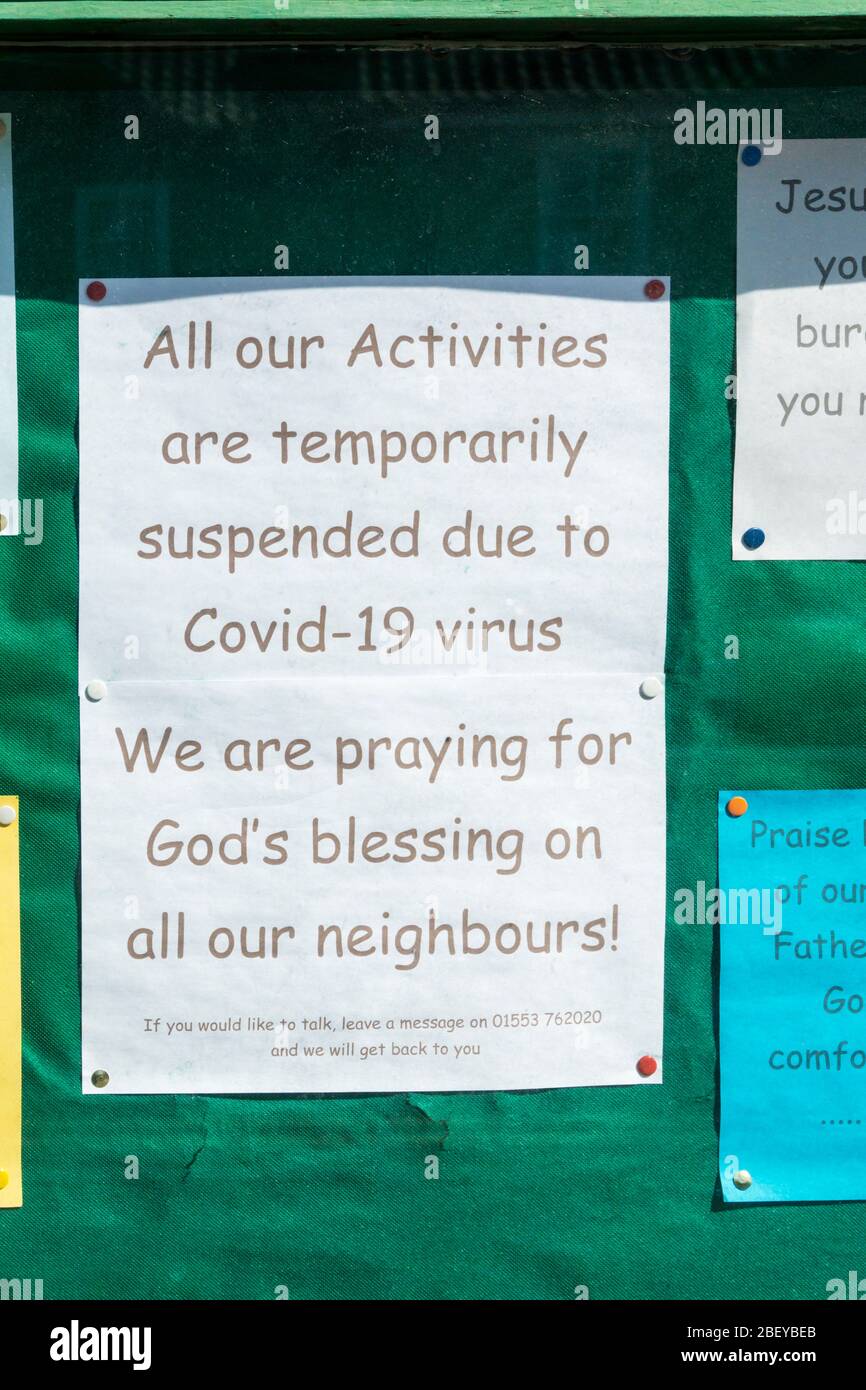 Ein Schild auf einer Kirchenwand besagt, dass alle Aktivitäten wegen des Covid-19 Virus ausgesetzt sind. Sie beten für Gottes Segen auf ihren Nachbarn. Stockfoto