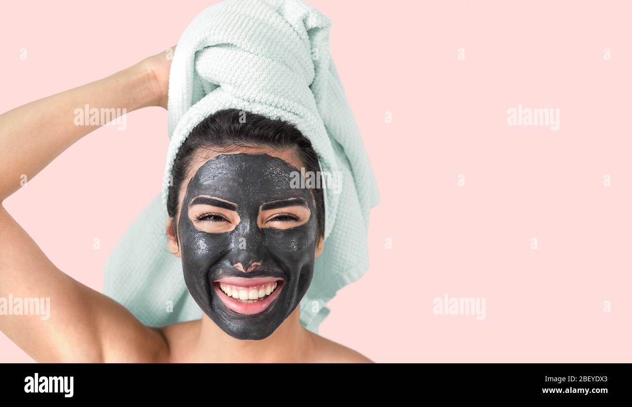 Glücklich lächelnd Mädchen Anwendung Gesichts schwarze Maske - Junge Frau mit Hautpflege Reiniger Spa Tag Stockfoto