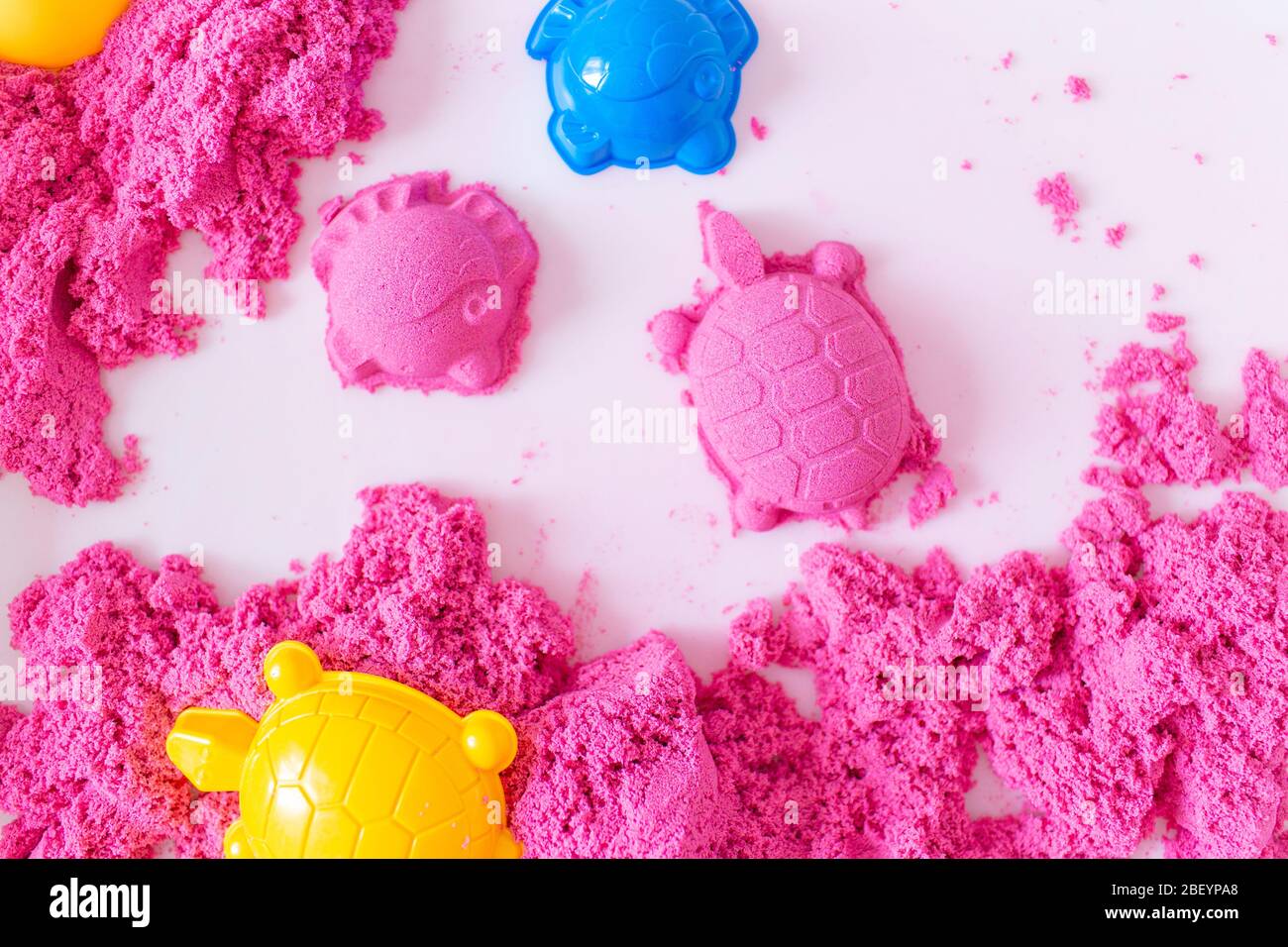 Kleines Mädchen spielt mit rosa Kinetic Sand zu Hause. Frühzeitige Ausbildung. Vorbereitung auf die Schule. Entwicklung Stockfoto