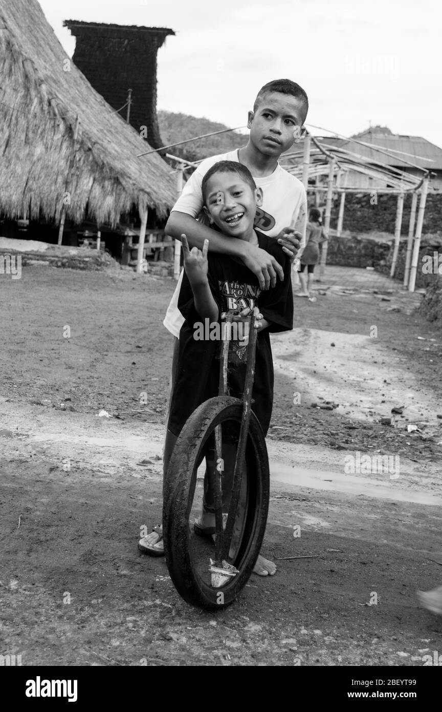 Kelimutu, East Nusa Tenggara / Indonesien - Januar 13 2015: Porträt eines Jungen in einem traditionellen Dorf, der mit einem Rad als Spielzeug spielt. Schwarz und Weiß Stockfoto