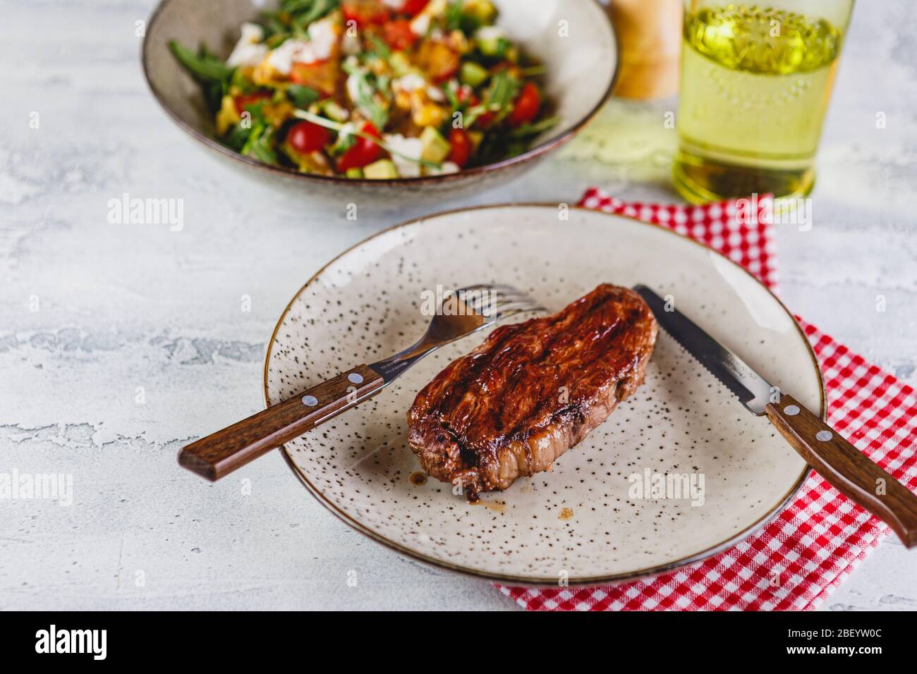 Gegrillte Steaks und Gemüsesalat auf hellem Hintergrund. Tischeinstellung, Speisekonzept. Banner. Stockfoto