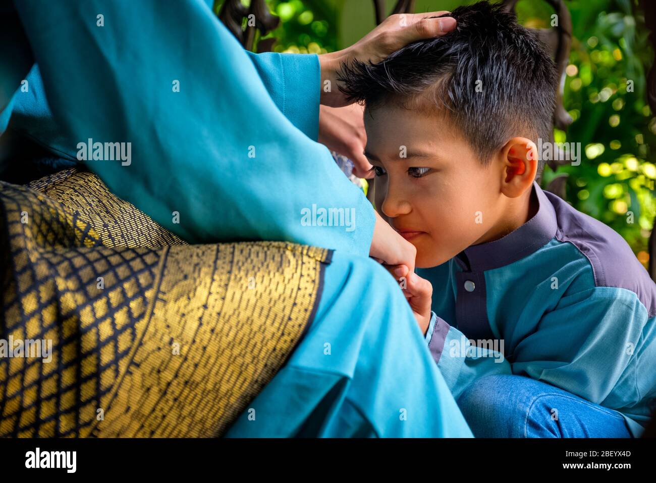 Nahaufnahme des malaiischen muslimischen Sohnes in traditioneller Tracht zeigt Entschuldigung Geste zu seinem Elternteil während der Aidilfitri Feier. Raya und muslimische Mode-Atti Stockfoto