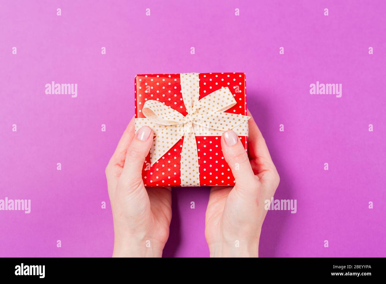 Nahaufnahme der Frau Hände halten Geschenk Geschenkbox auf lila Hintergrund. Urlaub Valentinstag Muttertag Hochzeit Konzept. Freier Speicherplatz. Kopierbereich. Stockfoto