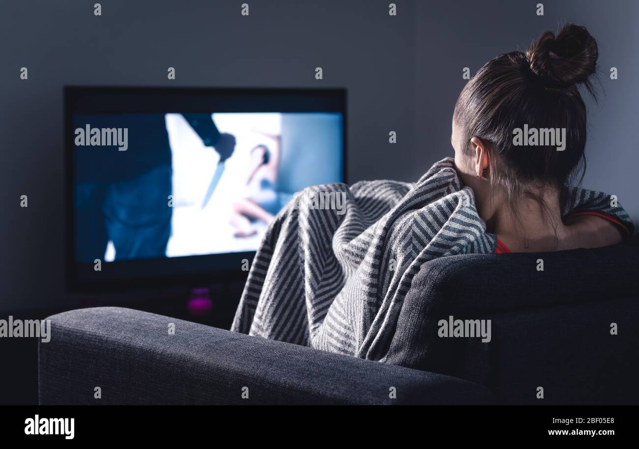 Grusel Horror Film im fernsehen. Erschrockenen Frau beobachten Stream Service versteckt unter Decke auf Couch in der Nacht. Schlaflose Person, die Serien oder Filme auf dem fernseher streamt. Stockfoto