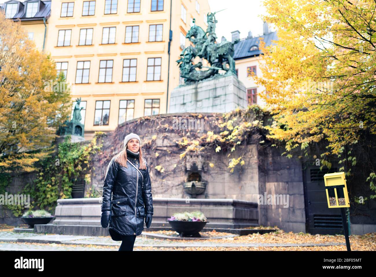 Person, die im Winter oder Herbst in Stockholm und der Altstadt (Gamla Stan) spazieren geht. Gelbe Herbstfarben in Bäumen und Blättern. Frau im Urlaub in Schweden. Stockfoto