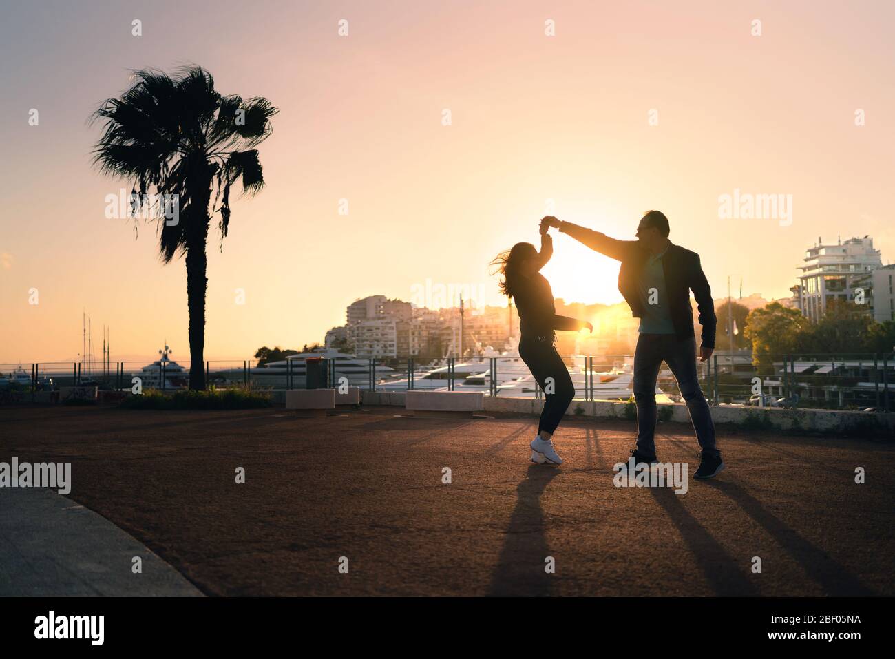 Paar tanzen auf der Straße. Spontaner spielerischer Moment mit Bewegung. Kerl und Mädchen mit Spaß und Dating. Stylische Trendsleute bei Sonnenuntergang. Urbanes Leben. Stockfoto