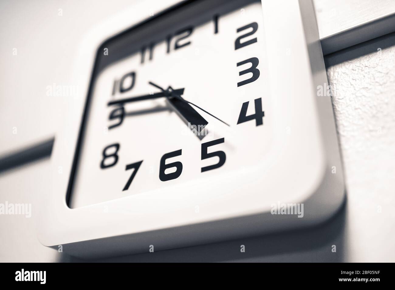 Moderne Uhr an der Wand. Fast 5 Uhr nachmittags oder morgens. Im Laufe der Zeit bei der Arbeit. Dramatischer Winkel. Stockfoto