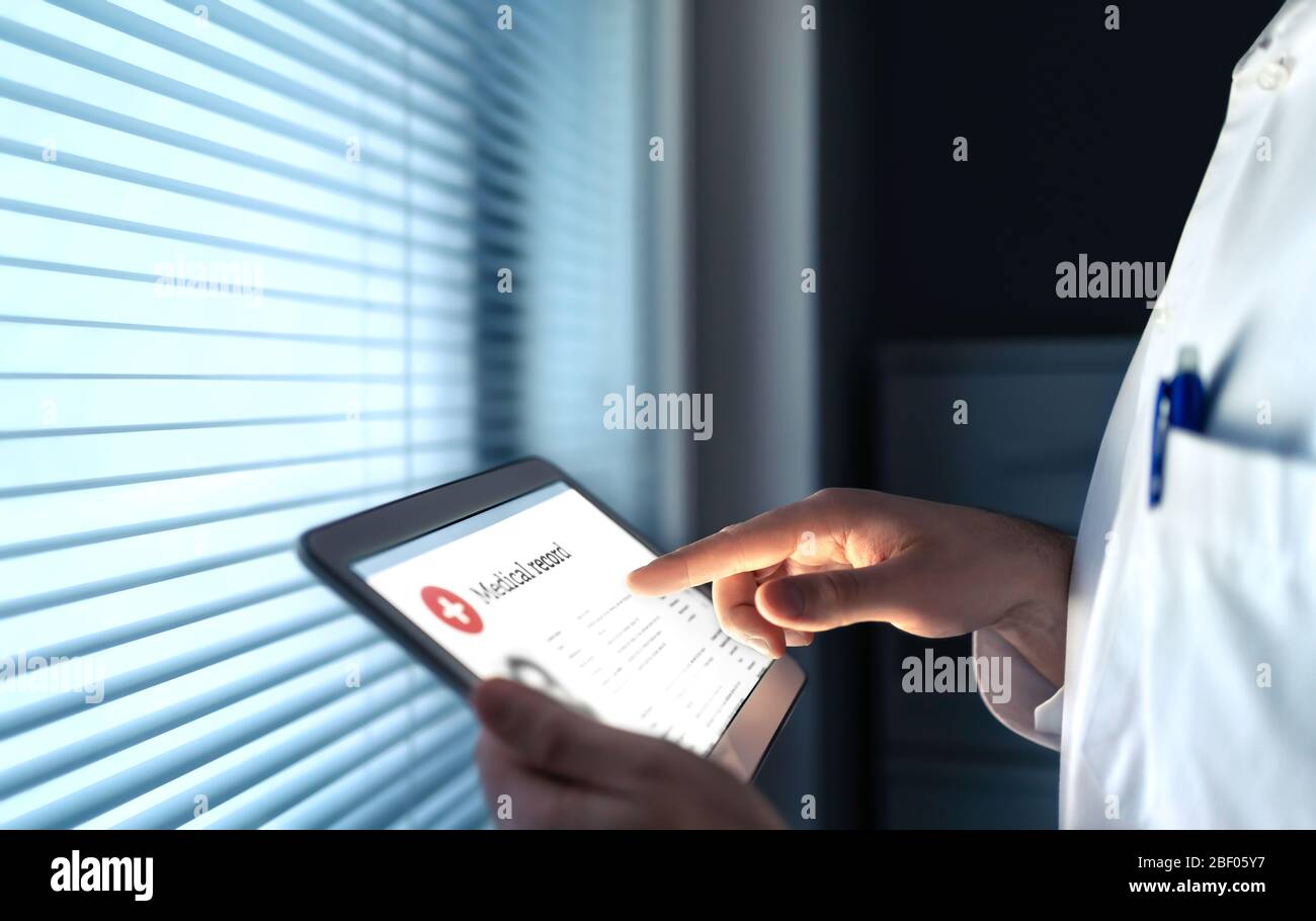 Arzt, der elektronische Krankenakte (EMR) auf dem Tablet verwendet, um Gesundheitsinformationen für den Patienten zu lesen. Digitale Krankengeschichte oder -Bericht. Stockfoto
