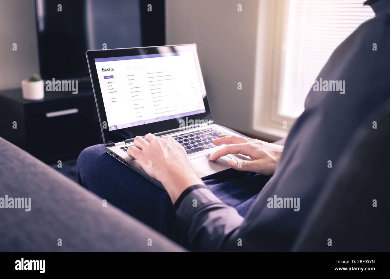 Mann liest E-Mails und benutzt Laptop im Wohnzimmer. Überprüfen der empfangenen elektronischen Web-Mail und Antworten auf Nachrichten. Posteingang für Mockup. Stockfoto