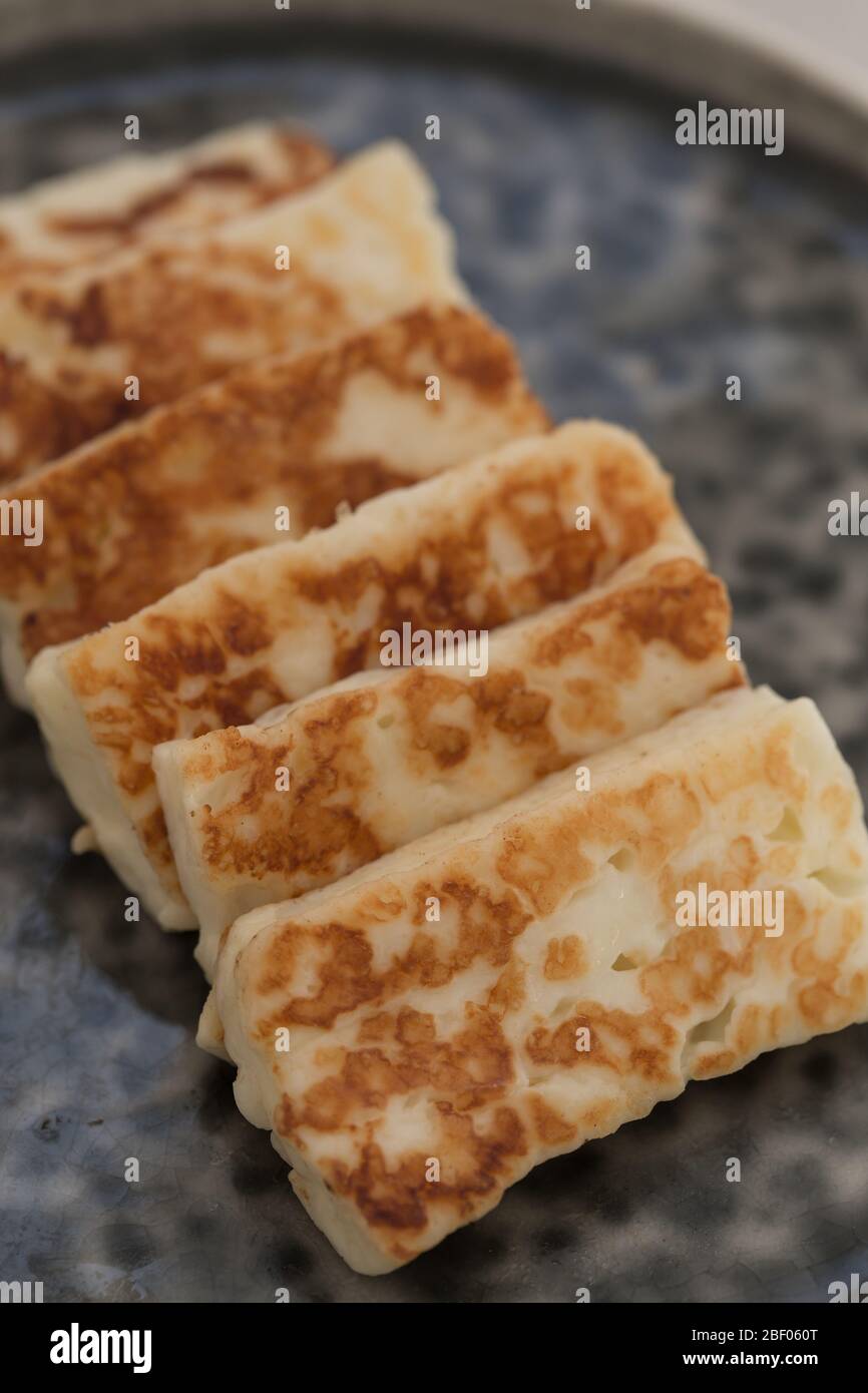Vertikales Bild von gebratenem Halloumi Käse auf einem grauen Keramik Geschirr platziert Stockfoto