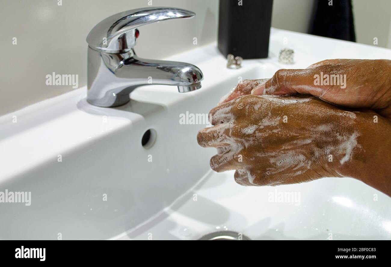 Schwarze Frau, die sich gewissenhaft die Hände mit Seife wäscht. Selektiver Fokus auf Hände. Desinfektion. Hygienekonzept. Stockfoto