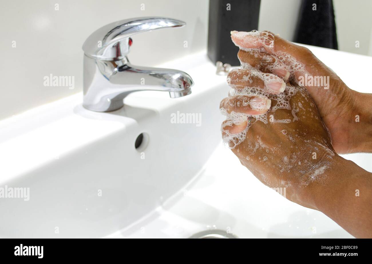 Schwarze Frau, die sich gewissenhaft die Hände mit Seife wäscht. Selektiver Fokus auf Hände. Desinfektion. Hygienekonzept. Stockfoto
