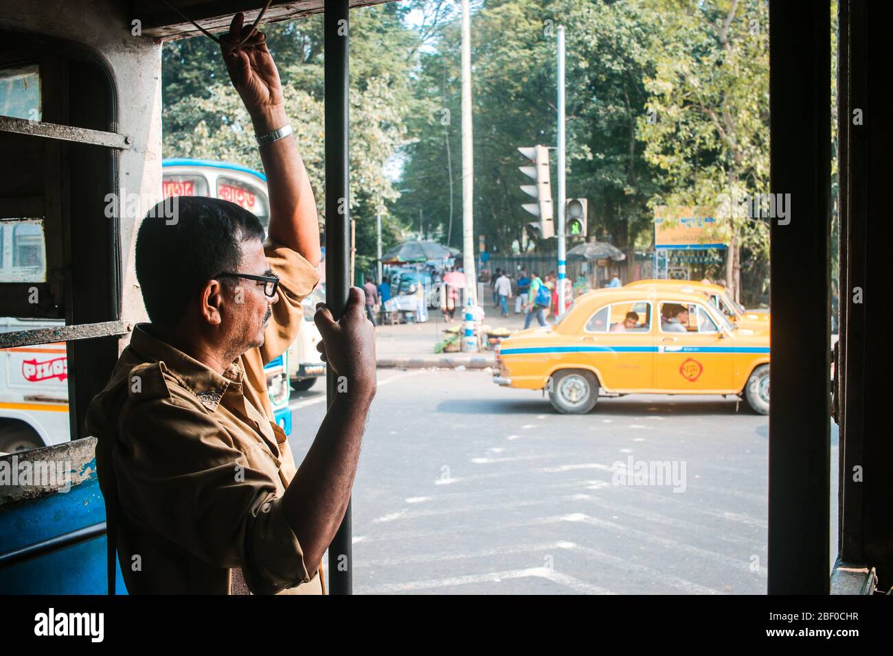 Ein Dirigent steht am Eingang einer Straßenbahn in Kalkutta, Indien. Stockfoto