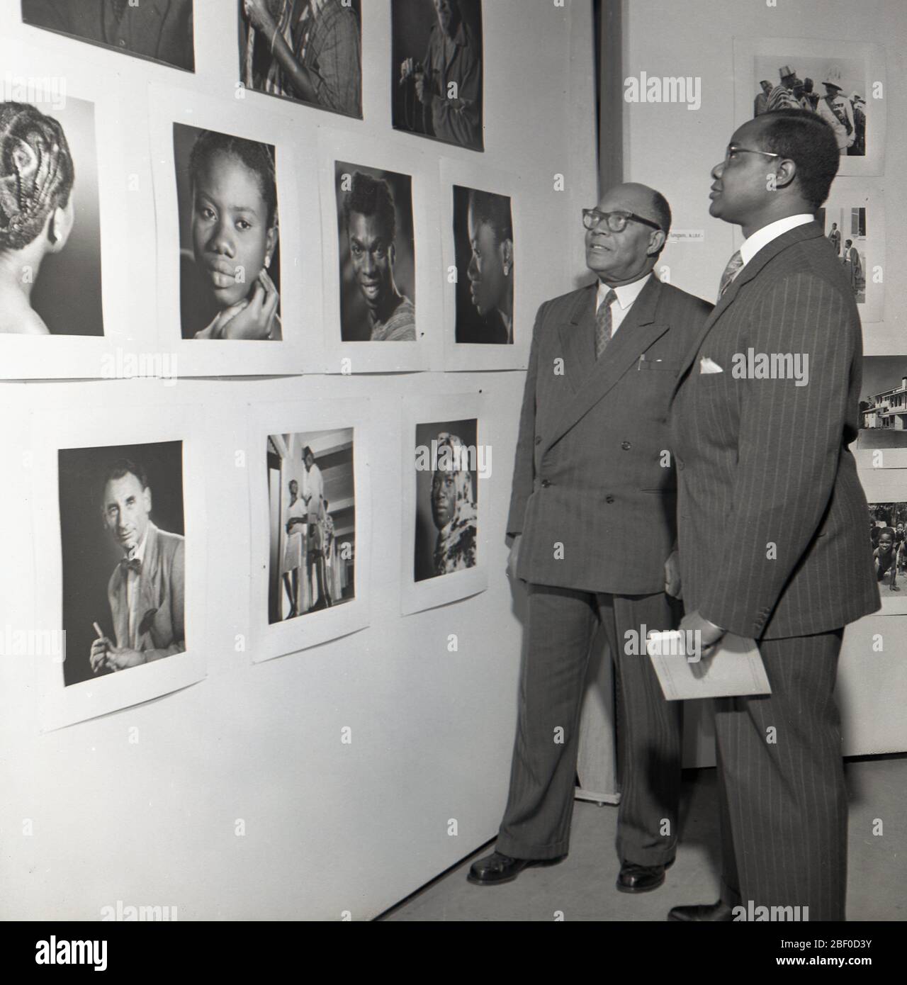 1950, historisch, zwei geeignete afrikanische Gäste bei einer Fotoausstellung, die eine Auswahl von Bildern aus dieser Zeit, London, England, Großbritannien, von der Gold Coast, anschaute. Die Goldküste in Westafrika war von 1821 bis zu ihrer Unabhängigkeit 1957 eine britische Kolonie. Stockfoto
