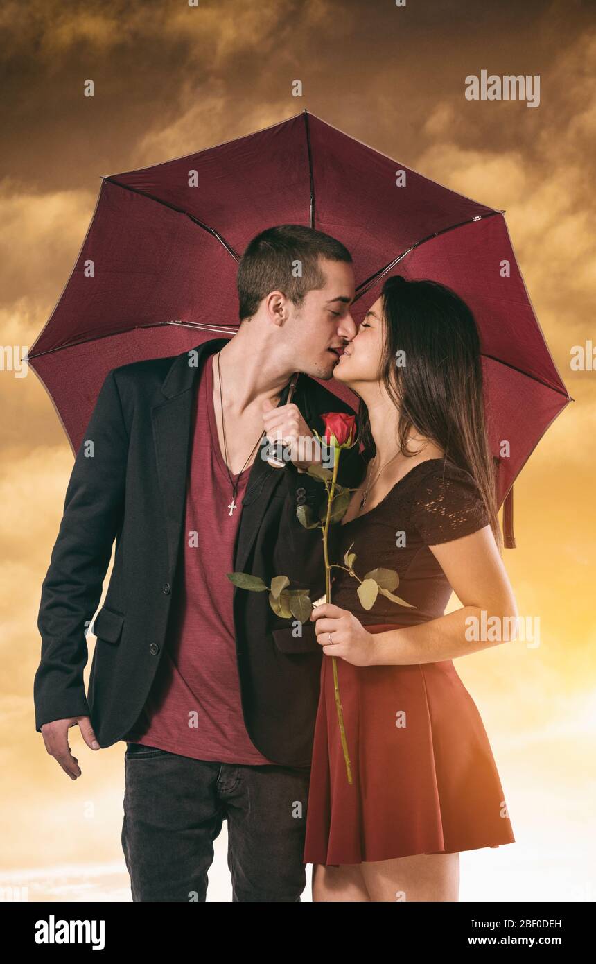 Freundin und Freund mit einem leidenschaftlichen Kuss in einem Regenschirm gerahmt Stockfoto