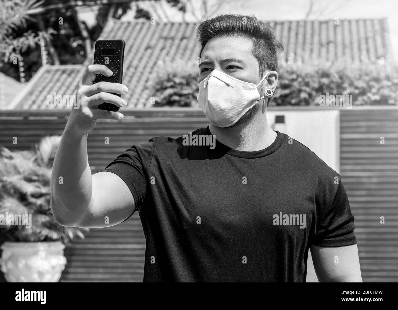 Porträt eines Mannes mit Gesichtsmaske, der ein Selfie auf dem Telefon nimmt. Isolierter Mann zu Hause während der Quarantäne. Stockfoto