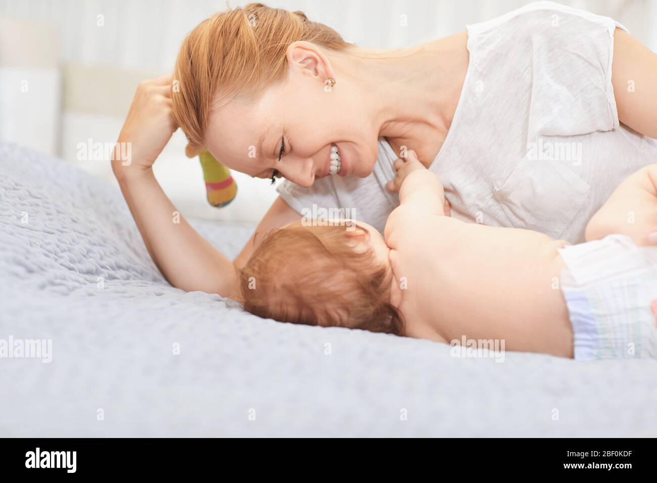 Mutter umarmte ihr Baby auf einem Bett Stockfoto