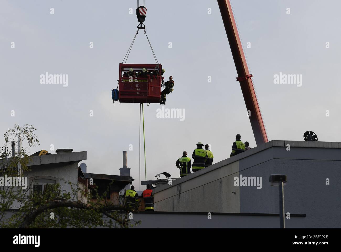 Murnau, Deutschland. April 2020. Feuerwehrleute begutaten das Feuer von einem Kran aus. Laut Polizei war am Donnerstagnachmittag ein Dachstuhl im Dorfzentrum in Brand geraten. Die Flammen breiteten sich jedoch auf zwei weitere Häuser aus, alle drei wurden schwer beschädigt. Kredit: Angelika Warmuth/dpa/Alamy Live News Stockfoto