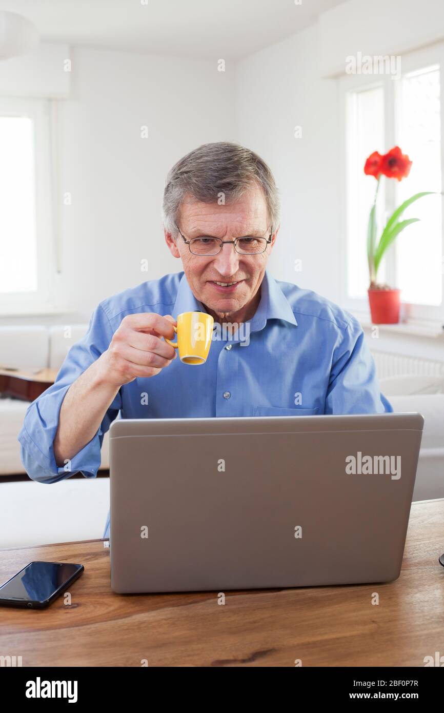 Ältere oder ältere Geschäftsmann trinken Espresso vor einem Computer in seinem Home Office - konzentrieren Sie sich auf das Gesicht Stockfoto