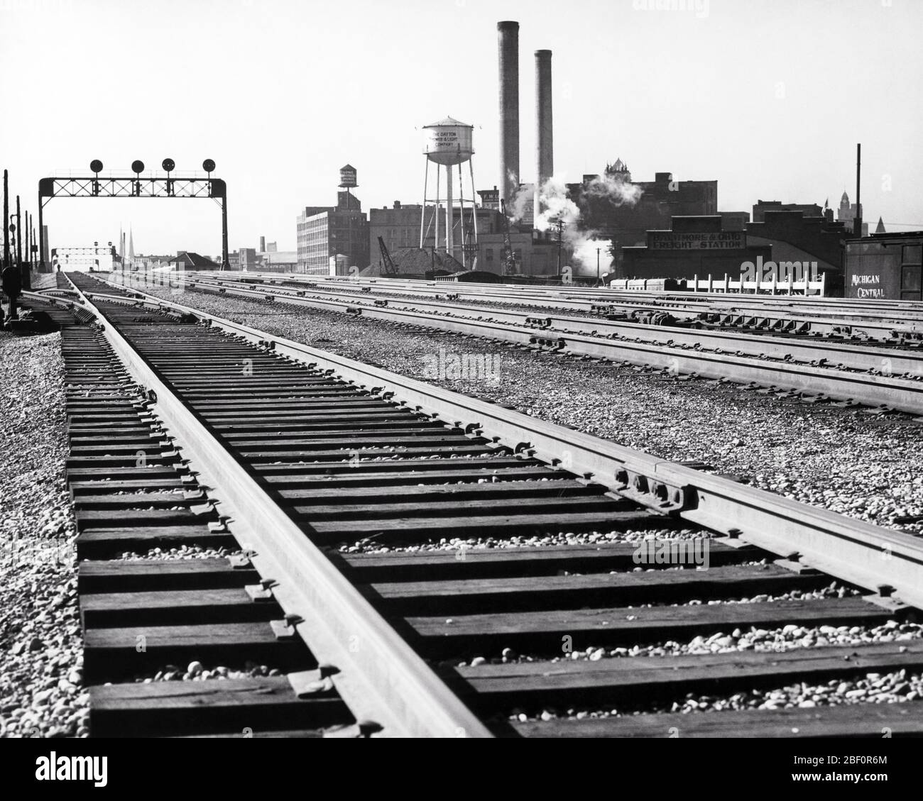 1960S GUT GEPFLEGTE EISENBAHNSCHIENEN STAHLSCHIENEN HOLZKREUZ TIES SCHARFEM BALLAST IN DER INDUSTRIELLEN FABRIK GEBIET VON DAYTON OHIO USA - R4680 HAR001 HARS SPIKES KONZEPT VERBINDUNG KONZEPTIONELLE DAYTON EISENBAHNEN SYMBOLISCHE KONZEPTE MAINLINE OH OHIO SCHWARZ UND WEISS FABRIKEN HAR001 MIDWEST ALTMODISCHE SCHIENEN DARSTELLUNG SMOKESTACKS Stockfoto