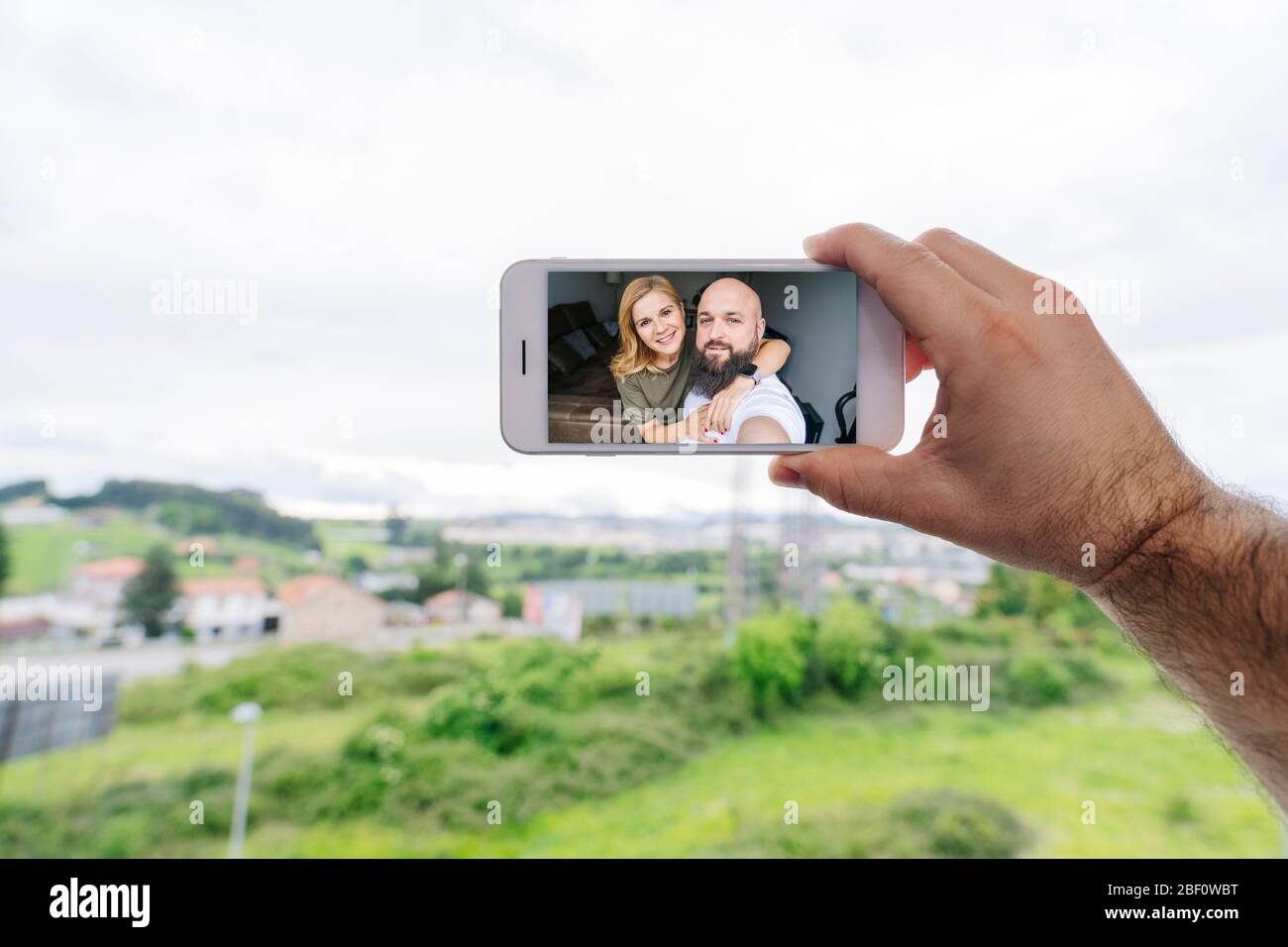 Ein Paar Mann und Frau machen ein Selfie-Foto mit dem Handy im Fenster ihres Hauses Stockfoto