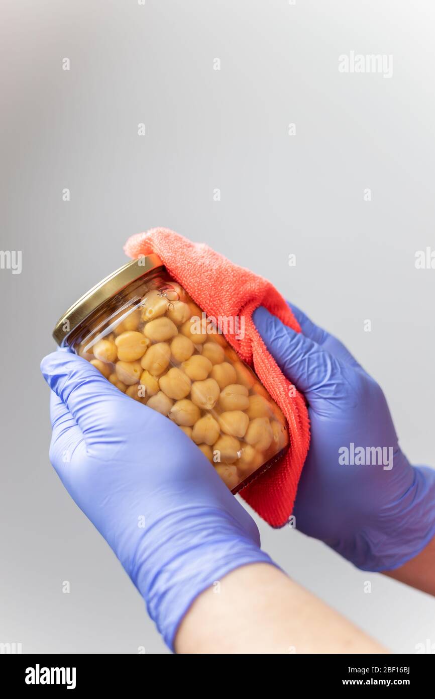 Handschuppen reinigen nach dem Einkaufen ein Glas Kichererbsen, um die Ausbreitung des Coronavirus zu verhindern Stockfoto