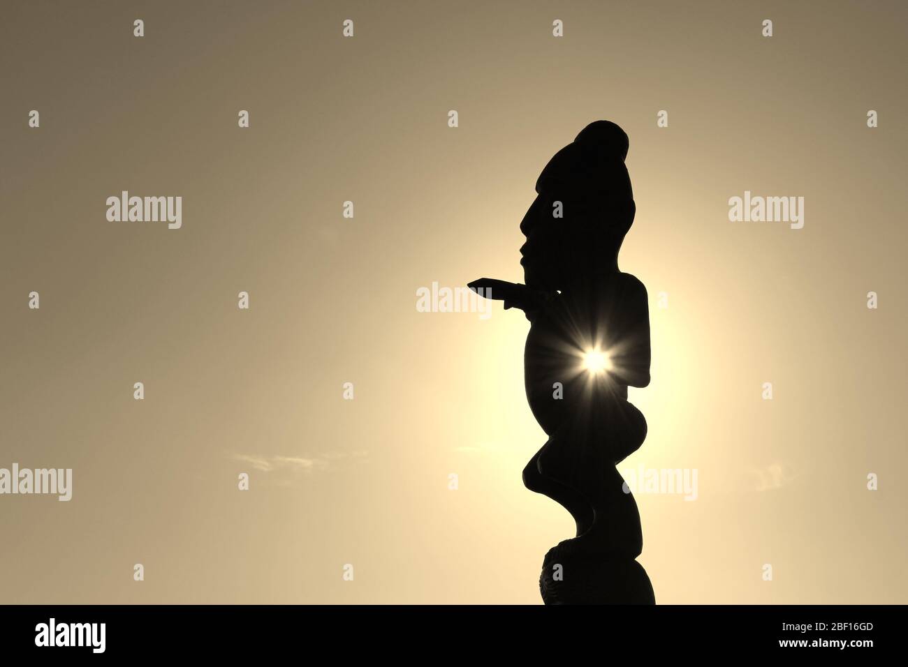 Mystische M?ori Skulptur in atmosphärischer Perspektive mit der Sonne, die durch Körper und Arm scheint, was eine beeindruckende Wirkung erzeugt. Die sogenannte Pou Stockfoto